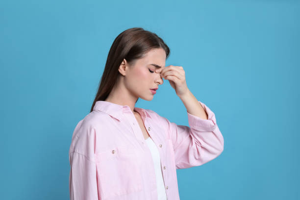 istock Young woman suffering from headache on light blue background 1415167111