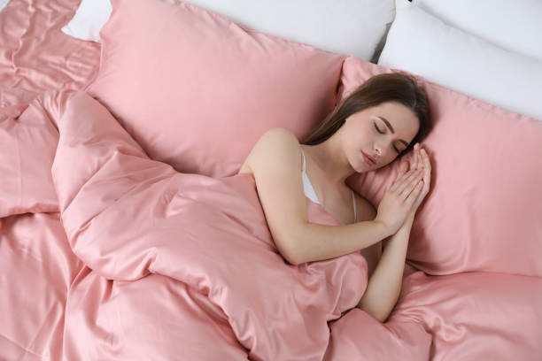 young woman sleeping in comfortable bed with silky linens, above view - sheet sleeping women bed imagens e fotografias de stock