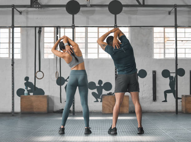 couple de gymnastique en forme, actif et en bonne santé s’étirement, se préparer et se préparer pour l’entraînement, l’entraînement et l’exercice dans le centre de bien-être. sportif, athlétique ou fort homme et femme s’échauffant pour l - human muscle back muscular build men photos et images de collection