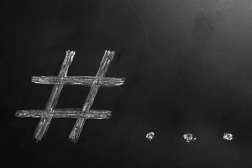 Hashtag symbol and ellipsis drawn with chalk on blackboard. Space for text