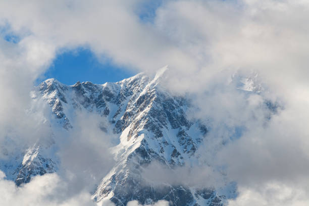 istock Clouds over the snow covered mountains. High mountains peak, winter landscape. 1415169882