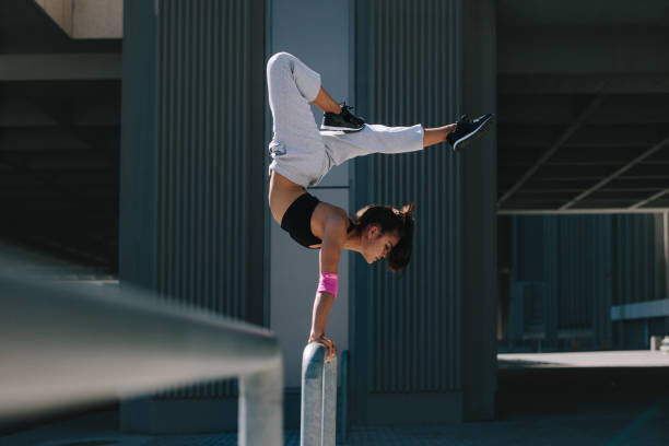 Sportswoman doing handstand in city Sportswoman doing a handstand on railing outdoors. Flexible female athlete performing extreme sports in an urban space. free running stock pictures, royalty-free photos & images
