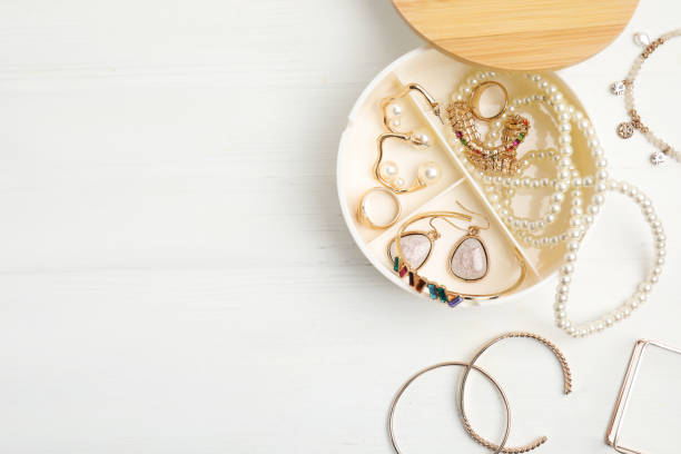 шкатулка для украшений со стильной бижутерией на белом деревянном столе, плоская укладка места для текста - earring gold jewelry contemporary стоковые фото и изображения