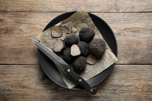 truffes noires et couteau dans l’assiette sur table en bois, vue de dessus - truffe champignon photos et images de collection