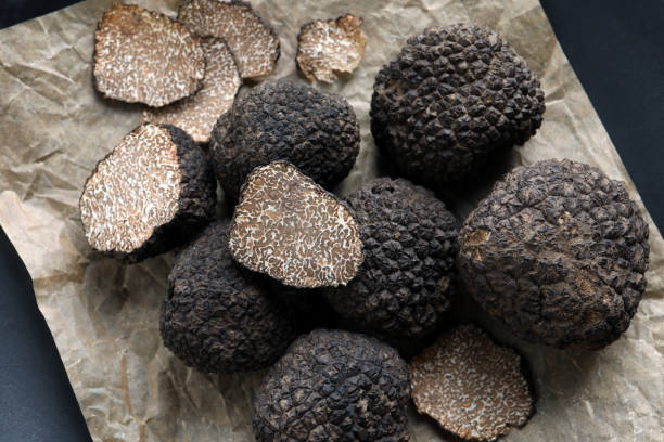 istock Whole and cut black truffles on parchment, top view 1415174923
