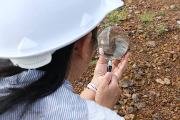 istock Female geologist using a magnifying glass examines nature, analyzing rocks or pebbles. Researchers collect samples of biological materials. Environmental and ecology research. 1415175254
