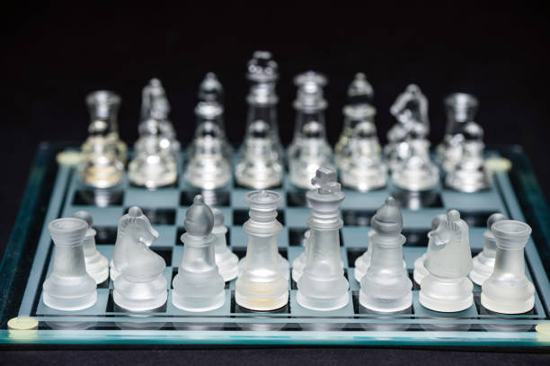 istock glass, transparent chess pieces on a checkerboard, selective focus, close-up, isolated on black 1415177365