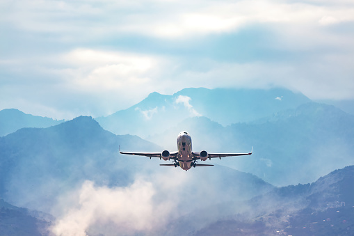 jet flight travel concept stock photo. Airplane fly above amazing blue misty mountains
