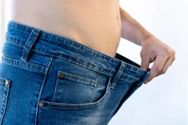 A man measures old jeans after a successful diet. Concept of healthy eating.