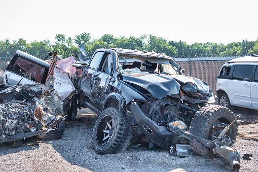 The smashed in front of a modern pickup truck following a automobile wreck, sitting in a salvage tow yard.