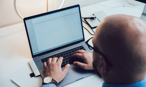 istock Crop bald man typing on laptop keyboard while sitting in workplace 1415183602