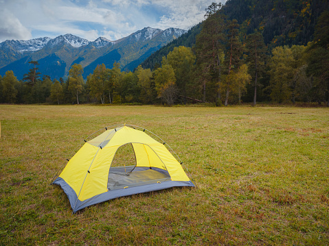 trip to Caucasus mountains, Arkhyz, Teberdinsky reserve. concept of discovery and exploration of wild places in early autumn. yellow tent in autumn valley