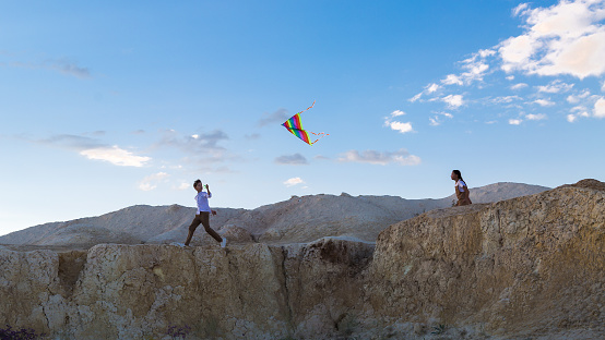 Children run with a kite on the slope high mountain, copy space.