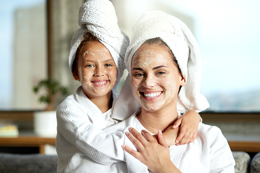 Loving, affectionate and happy mother and daughter having a relaxing spa day together. Portrait of a cheerful, smiling and joyful little girl enjoying a pamper session with her mom or single parent