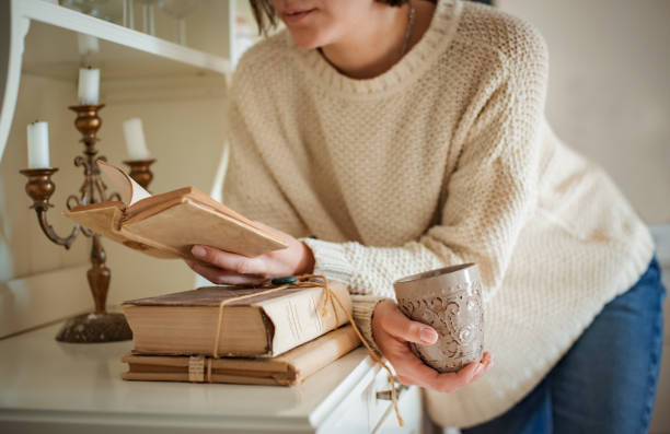 beautiful young woman reading book near at home - antique bed imagens e fotografias de stock