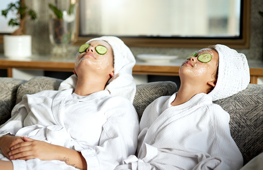 Beauty, relaxing and skincare for mother and daughter, enjoying a spa treatment at home. Little girl and parent bonding while doing hygiene, refreshing grooming. Females with cucumber, facial mask