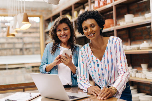 ceramistas felices sonriendo a la cámara mientras trabajan en su tienda - entrepreneur fotografías e imágenes de stock