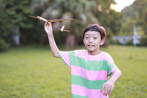 Boy playing with a plane on the park lawn
