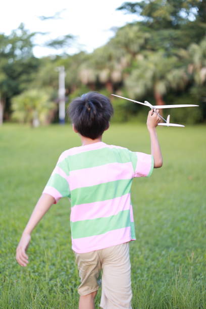 Boy playing with a plane on the park lawn