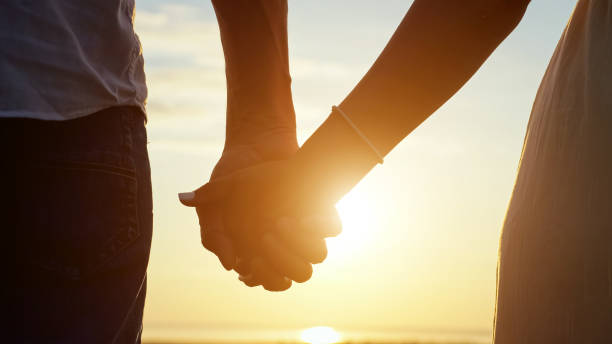 istock Couple takes each other hands at back sunset closeup 1415194338