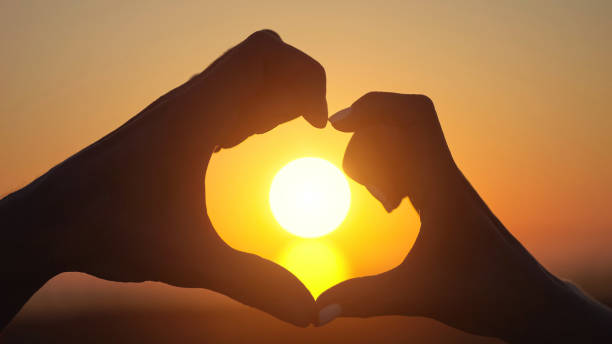 istock Couple shows heart with hands at back bright orange sunset 1415194350
