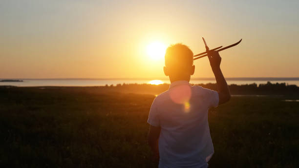 istock Junior schoolboy runs on meadow to launch airplane to sunset 1415194359
