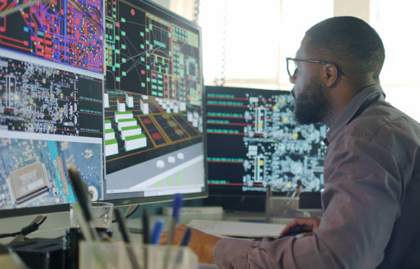 CAD electronics engineer A Stock image of an Afro-Caribbean male designing electronic circuit boards ( PCBs).
He’s sitting at a desk with a large computer screen displaying a variety of apps & PCB illustrations. electrical equipment stock pictures, royalty-free photos & images