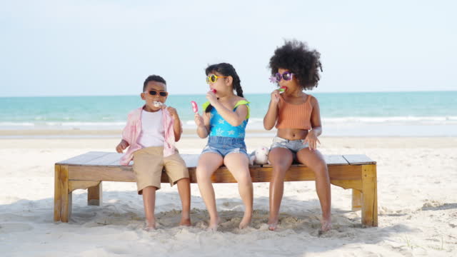 4K Group of Diversity children eating ice cream together at the beach on summer vacation.