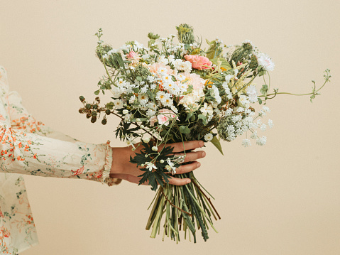 Bouquet of yellow and white flowers wrapped in paper cone with ribbon for present isolated on white background.