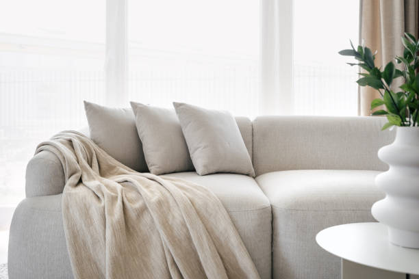Pillows and blanket on modern soft grey sofa Three grey pillows and blanket on grey soft sofa in living room with panoramic windows. Hypoallergenic concept. Relax idea. Home comfort. House interior details. Hotel room interior design plaid couch stock pictures, royalty-free photos & images