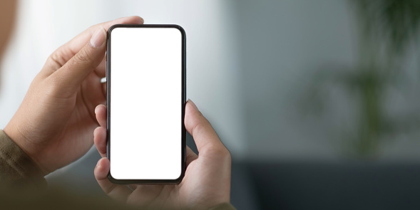 Mockup image blank white screen cell phone.women hand holding texting using mobile on sofa