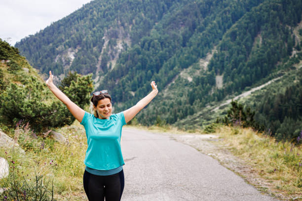 Chubby woman doing worming-up exercise in the mountains