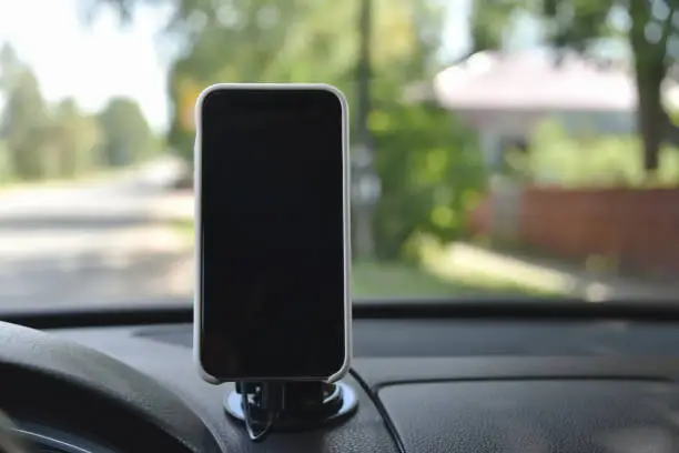Photo of Smartphone in a holder on the dashboard of a car.