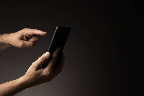 istock Hand holding smart phone with finger touching display, side view 1415202230