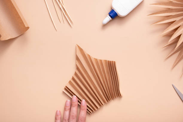 istock The accordion-folded paper blank is ready for gluing. Creative handwork to create tropical leaves. Master class 1415202287