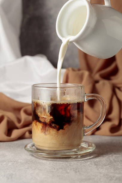 istock Pouring creme in a cup of coffee. 1415203275
