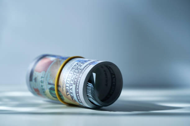 roll of 100 dollar bills against gray background