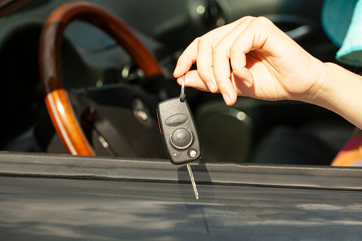 Car key in woman's hand with car