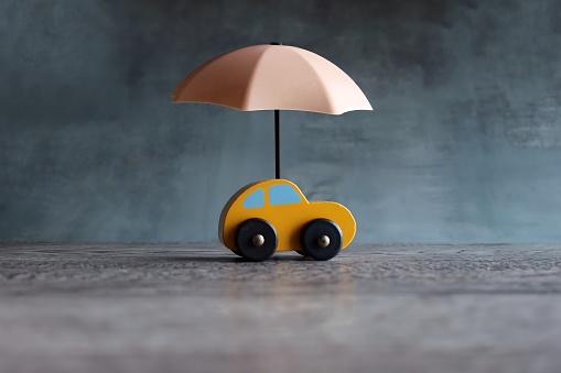 Umbrella and toy car with copy space. Car protection and insurance concept.