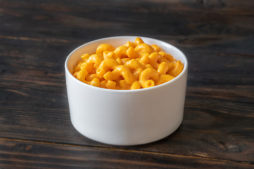 Bowl of macaroni and cheese on black background