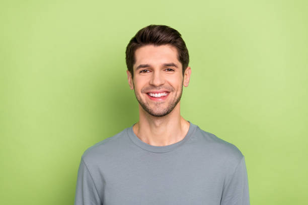 Photo of cool millennial brunet guy wear grey shirt isolated on green color background stock photo