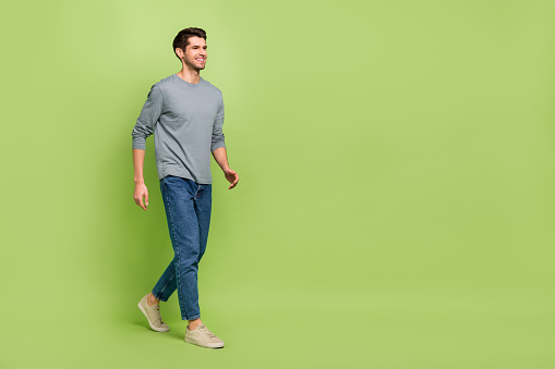 Full size profile side image of cheerful handsome shopaholic man visit shopping mall isolated on green color background.