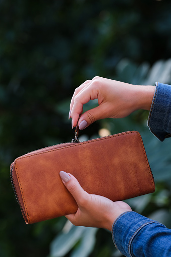 woman opens her wallet. brown wallet