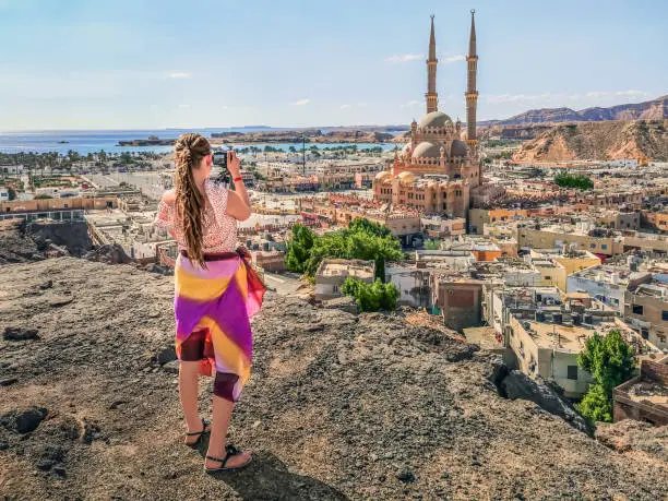 Photo of Blonde Caucasian girl takes photos from above on the background of the panorama of the Old Market in Sharm El Sheikh, Egypt