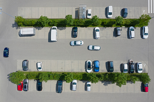 Aerial photograph of rows of cars parked in a large parking lot.