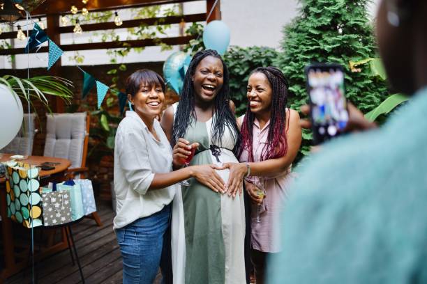 gruppo di donne che scattano foto durante un baby shower - gift mother women baby shower foto e immagini stock