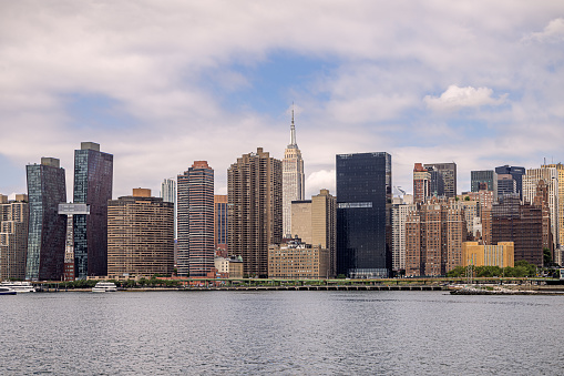 Long Island City, Queens, New York, NY, USA - July 7th 2022: View to the urban skyline of Manhattan with a view to Empire State Building across the East River