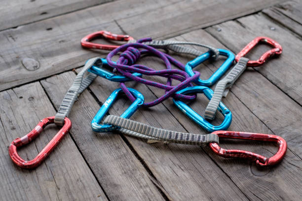 A middle-aged man in outdoor climbing gear demonstrates various rope-tying techniques in a natural forest setting. The images show detailed hand movements, knots, safety procedures, and climbing preparation. The background features trees and natural sunlight, creating an authentic outdoor atmosphere. The series includes close-up shots of hands and rope, instructional gestures, and portrait-style frames of the man demonstrating the knot-tying process.
