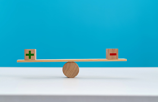 Wooden seesaw with plus and minus sign