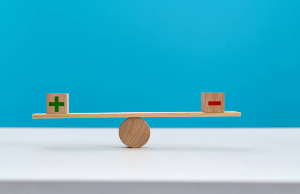 wooden seesaw with plus and minus sign - subtraction imagens e fotografias de stock